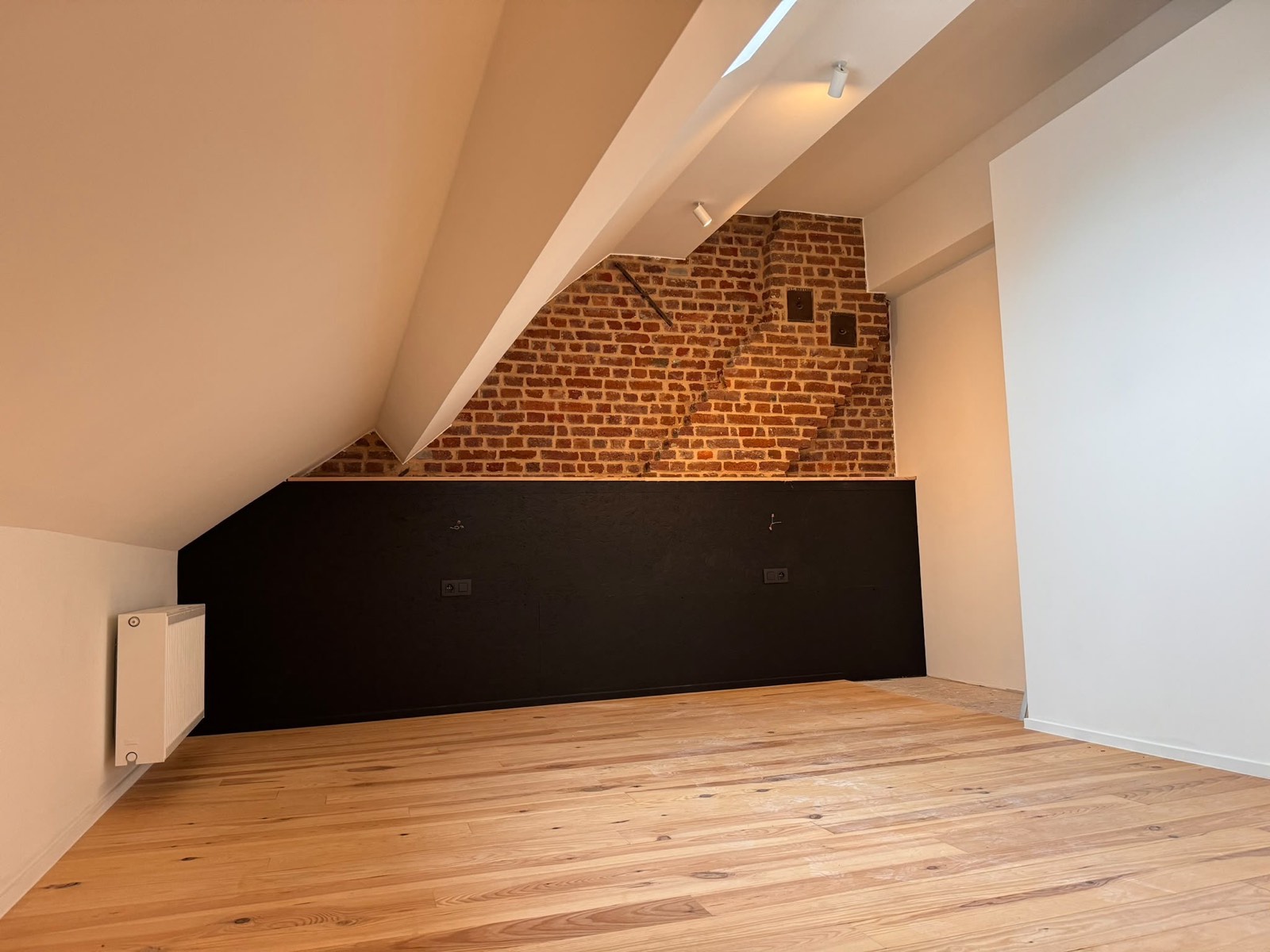 Combles aménagés avec parquet et mur en brique par RENOV HOUSE