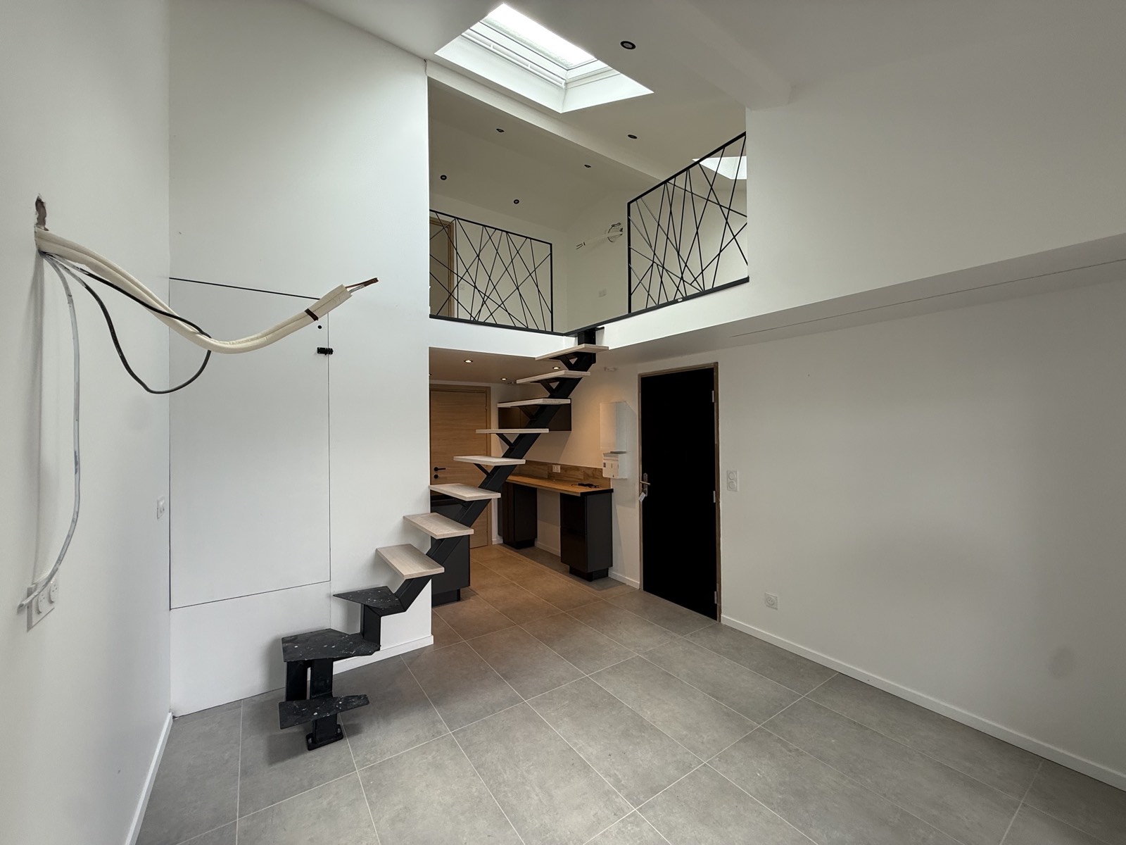 Escalier métallique noir desservant une mezzanine après travaux
