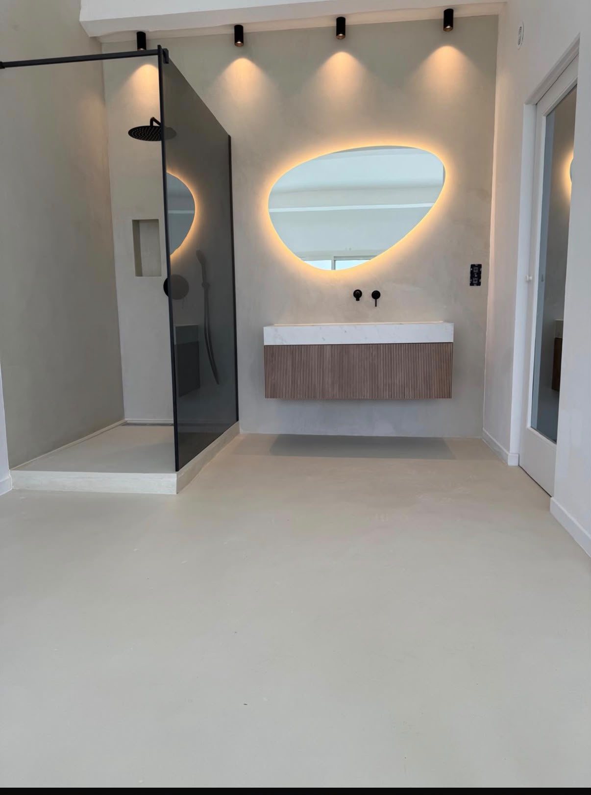 Salle de bain en béton ciré continu, meuble vasque et miroir rétroéclairé