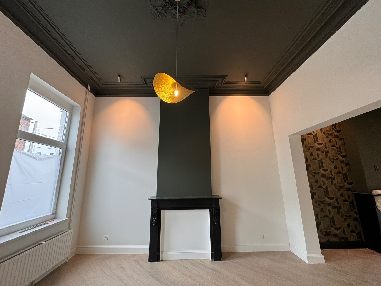 Séjour avec cheminée conservée et plafond peint en teinte foncée